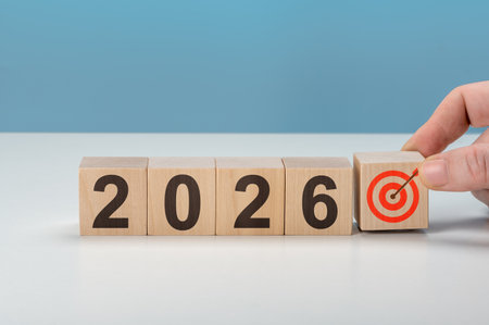 Man completing 2026 with target icon cube. Represents finishing business plans, achieving objectives, and successful strategy for new year aheadの写真素材