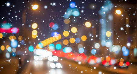 Falling snow on blurred city night background. Abstract bokeh lights for Christmas or winter holiday. Defocused urban street. Blue, red, and yellow festive backdropの写真素材