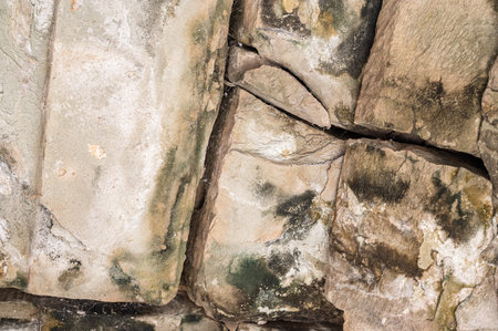 Abstract grunge background theme featuring rough surface of historic gray sandstone masonry with...