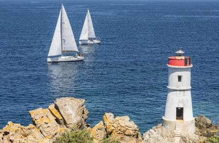 Two sailing boats with the rocks and white lighthouse
