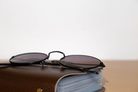 Glasses and brown notebook on a wooden tableの写真素材