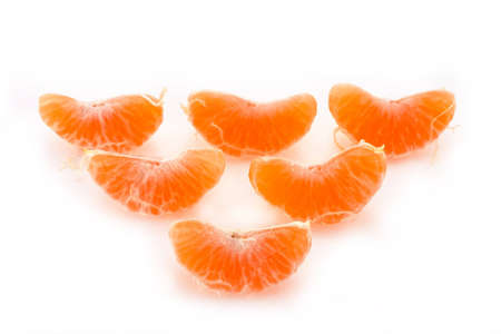 Slices of a ripe tangerine are fancifully placed on a white backgroundの写真素材