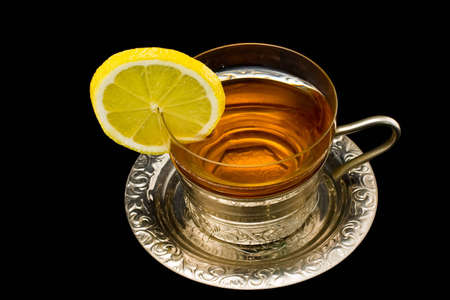 Transparent cup with tea and a lemon on a silver dishの写真素材