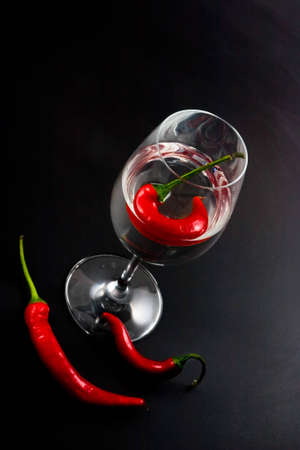 Red pepper in a glass with vodka on a black backgroundの写真素材