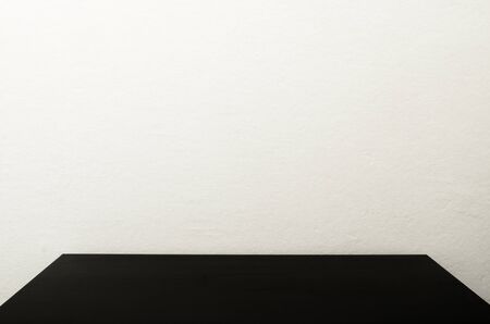 Black table in front of polished cement wall, white concrete loft style wall use for background.