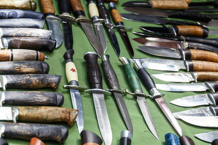 Hunting knives and knifes of large and small sizes lie on a table in a hunting and fishing store