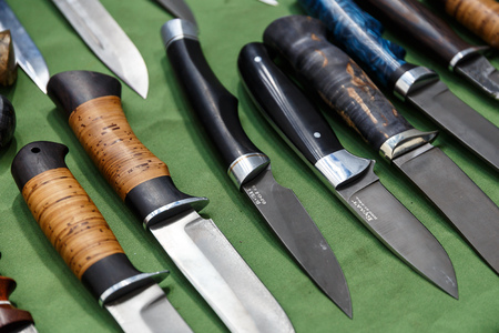 Hunting knives and knifes of large and small sizes lie on a table in a hunting and fishing store