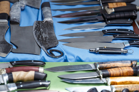 Hunting knives and knifes of large and small sizes lie on a table in a hunting and fishing store