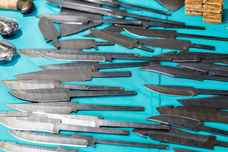 Hunting knives and knifes of large and small sizes lie on a table in a hunting and fishing store