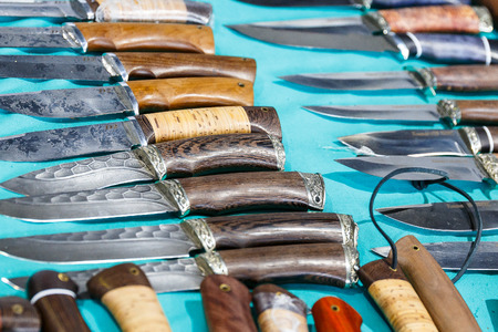 Hunting knives and knifes of large and small sizes lie on a table in a hunting and fishing storeの写真素材