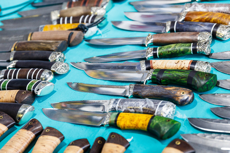Hunting knives and knifes of large and small sizes lie on a table in a hunting and fishing store