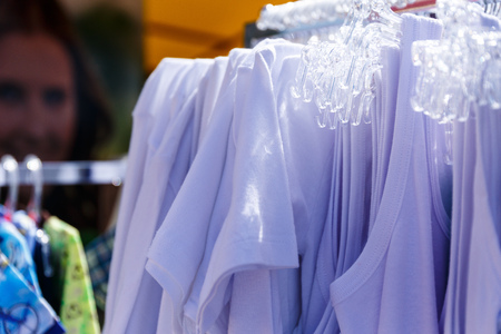 Baby clothes pants t-shirts sweaters shirts hanging on hangers in a shop outside in sunny weatherの写真素材