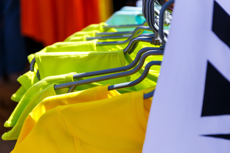 Baby clothes pants t-shirts sweaters shirts hanging on hangers in a shop outside in sunny weatherの写真素材