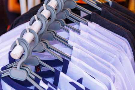Baby clothes pants t-shirts sweaters shirts hanging on hangers in a shop outside in sunny weather