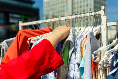 The hand chooses the clothes that hang on the hangers in the shop on the streetの写真素材