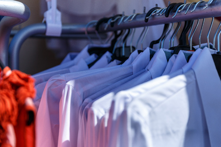 Men's and women's summer clothes sweatshirts shirts trousers jerseys coats jackets on the hanger in the shop on the streetの写真素材