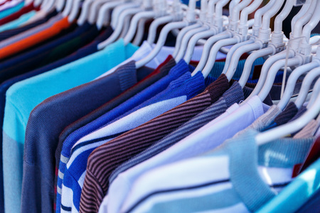 Men's and women's summer clothes sweatshirts shirts trousers jerseys coats jackets on the hanger in the shop on the streetの写真素材