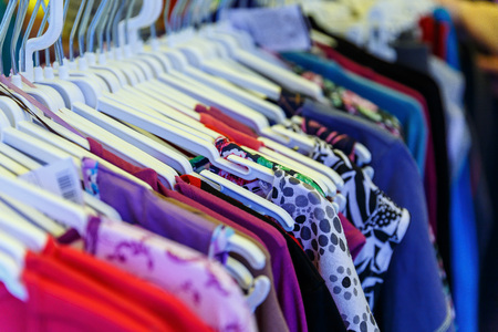 Men's and women's summer clothes sweatshirts shirts trousers jerseys coats jackets on the hanger in the shop on the streetの写真素材