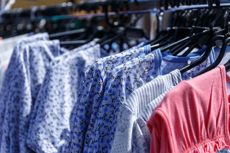 Men's and women's summer clothes sweatshirts shirts trousers jerseys coats jackets on the hanger in the shop on the streetの写真素材