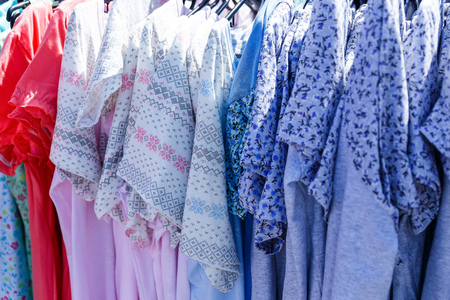 Men's and women's summer clothes sweatshirts shirts trousers jerseys coats jackets on the hanger in the shop on the streetの写真素材