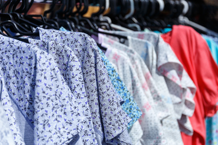 Men's and women's summer clothes sweatshirts shirts trousers jerseys coats jackets on the hanger in the shop on the streetの写真素材