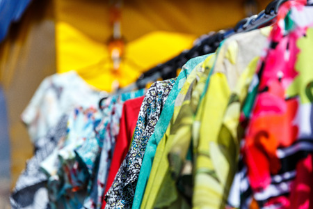 Men's and women's summer clothes sweatshirts shirts trousers jerseys coats jackets on the hanger in the shop on the streetの写真素材