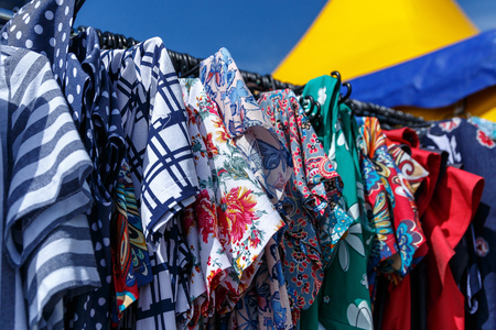 Men's and women's summer clothes sweatshirts shirts trousers jerseys coats jackets on the hanger in the shop on the streetの写真素材