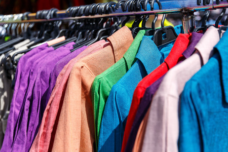Men's and women's summer clothes sweatshirts shirts trousers jerseys coats jackets on the hanger in the shop on the streetの写真素材