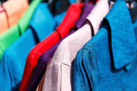 Men's and women's summer clothes sweatshirts shirts trousers jerseys coats jackets on the hanger in the shop on the streetの写真素材