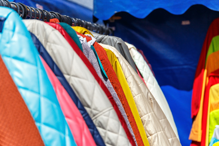 Men's and women's summer clothes sweatshirts shirts trousers jerseys coats jackets on the hanger in the shop on the streetの写真素材
