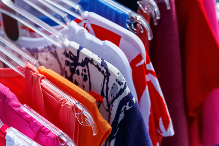 Men's and women's summer clothes sweatshirts shirts trousers jerseys coats jackets on the hanger in the shop on the streetの写真素材