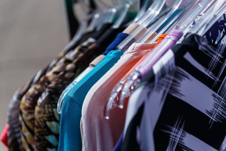 Men's and women's summer clothes sweatshirts shirts trousers jerseys coats jackets on the hanger in the shop on the streetの写真素材
