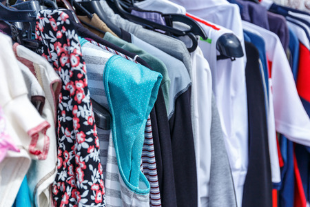 Men's and women's summer clothes sweatshirts shirts trousers jerseys coats jackets on the hanger in the shop on the streetの写真素材