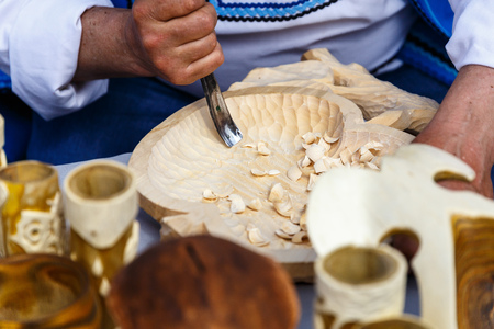 A man in a national Belarusian costume cuts out a wooden craftの写真素材