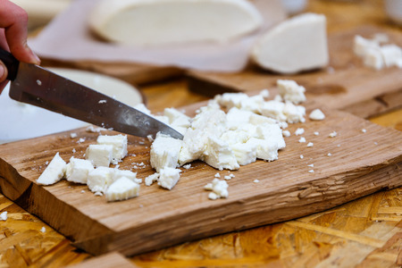 Woman cuts a delicious white goat cheese into piecesの写真素材