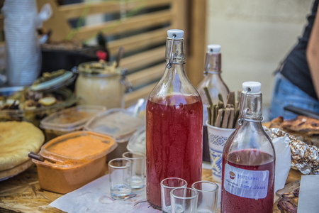 A loaf of bread, jam and a bottle of alcoholic tincture on a table laid for guestsの写真素材