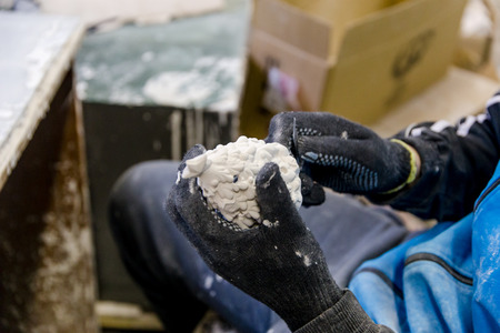 guy sculpture a Christmas toy from plaster in a factory of Christmas-tree toys