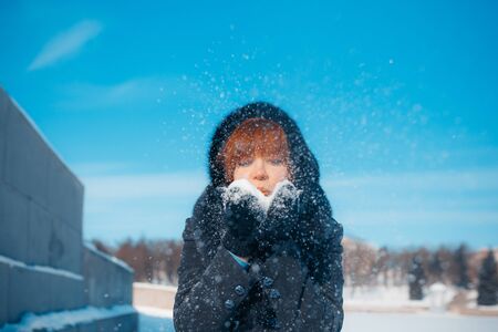 MINSK, BELARUS - February 1, 2017: red-hair woman blowing snow in hands in slow motionのeditorial素材