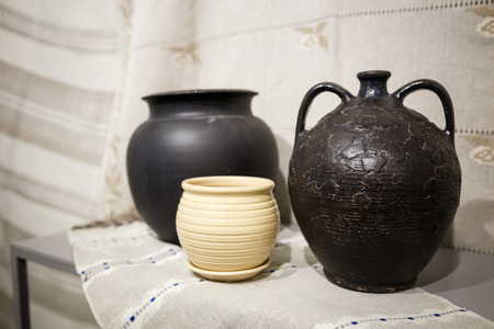 Old ceramic brown pot on a white tablecloth on a tableの写真素材