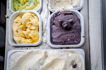 Boxes with different types and tastes of Italian natural gelato ice cream in a showcaseの写真素材