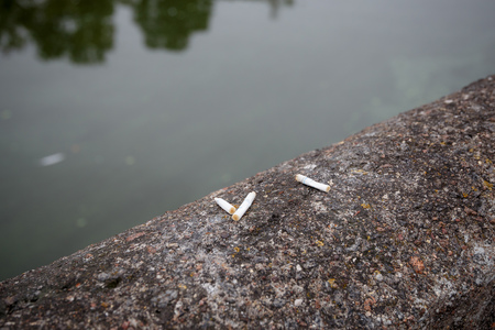 cigarette butts on a stone parapet by the lakeの写真素材