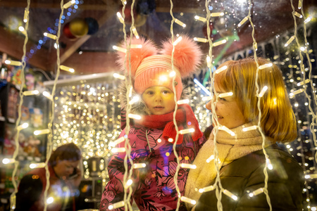 MINSK, BELARUS - 20 DECEMBER, 2018: mom holds her little daughter in her arms they look out of the window with Christmas lightsのeditorial素材