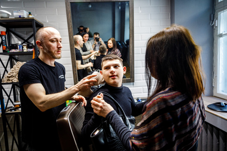 MINSK, BELARUS - 1 APRIL, 2019: a guy with down syndrome get a haircut in barbershopのeditorial素材