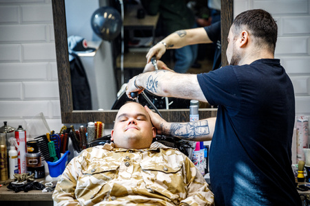 MINSK, BELARUS - 1 APRIL, 2019: a guy with down syndrome get a haircut in barbershopのeditorial素材