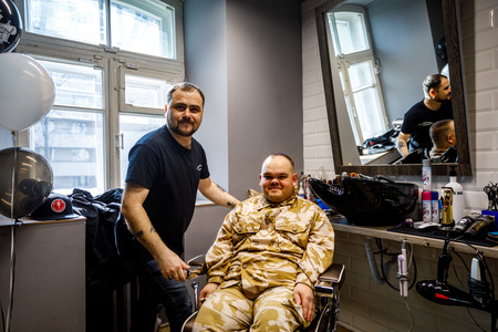 MINSK, BELARUS - 1 APRIL, 2019: a guy with down syndrome get a haircut in barbershopのeditorial素材