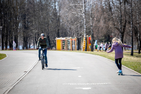 MINSK, BELARUS - 1 MARTH, 2019: children and adults walk in the park and ride roller skates and...
