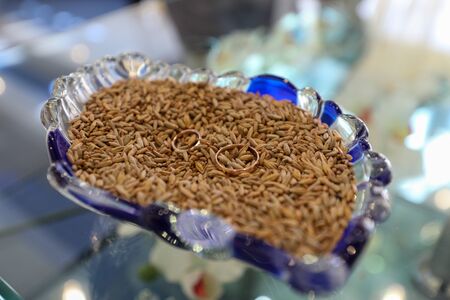 wedding rings lie on a plate with riceの写真素材