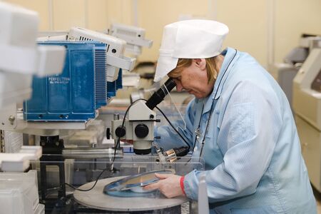 MINSK, BELARUS - February 25, 2020: Electronics Factory Worker a Printed Circuit Board Through a Digital Microscope High Tech Factory Facilityの写真素材