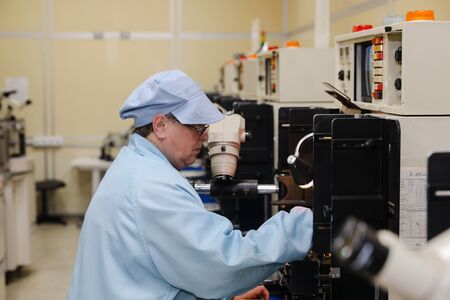 MINSK, BELARUS - February 25, 2020: Electronics Factory Worker a Printed Circuit Board Through a Digital Microscope High Tech Factory Facilityの写真素材