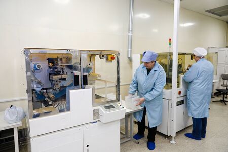 MINSK, BELARUS - February 25, 2020: Electronics Factory Worker a Printed Circuit Board Through a Digital Microscope High Tech Factory Facilityの写真素材